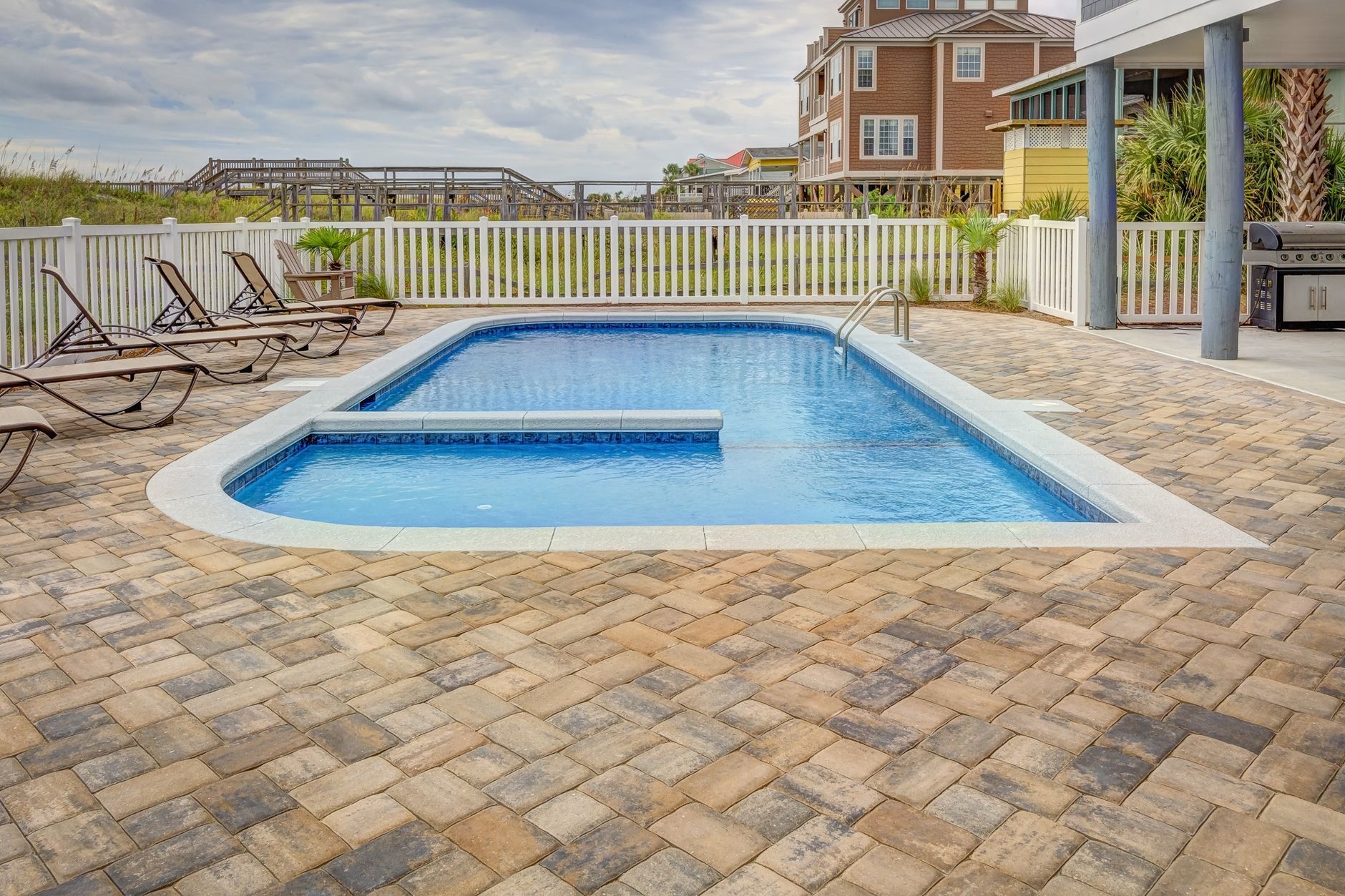 Relaxing poolside patio with sun loungers and villas, the kind of backyard retreat a hidden leak can quietly damage.