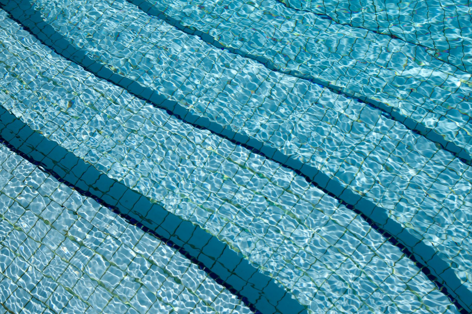 Close-up of crystal clear swimming pool water over a tiled surface, the result of a leak-free, properly maintained pool.